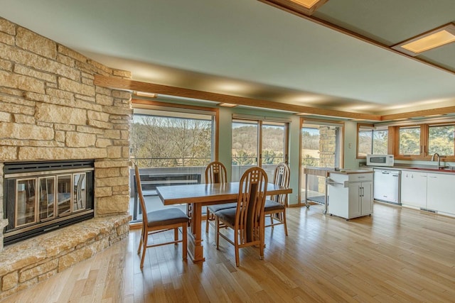 dining space featuring light wood-style flooring, a fireplace, and a wealth of natural light