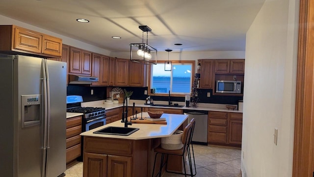 kitchen with a center island with sink, brown cabinetry, appliances with stainless steel finishes, light countertops, and a sink