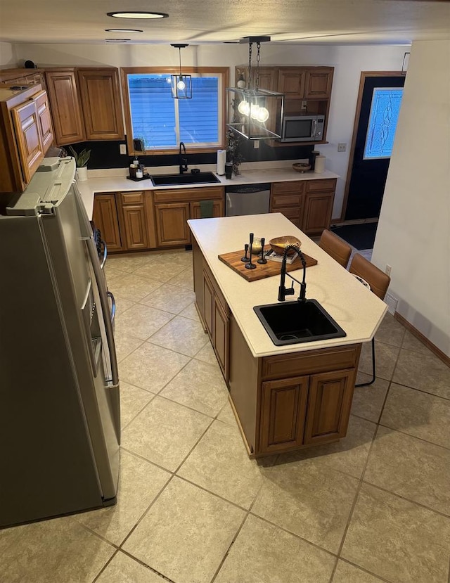 kitchen with a breakfast bar area, stainless steel appliances, a sink, light countertops, and hanging light fixtures