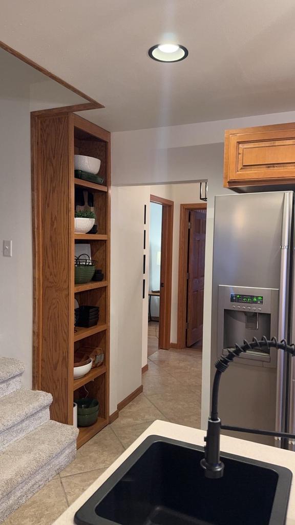 kitchen featuring light tile patterned floors, light countertops, a sink, and stainless steel fridge with ice dispenser