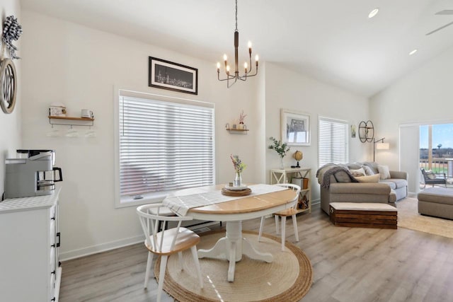 dining area featuring lofted ceiling, a chandelier, light wood-style flooring, and baseboards