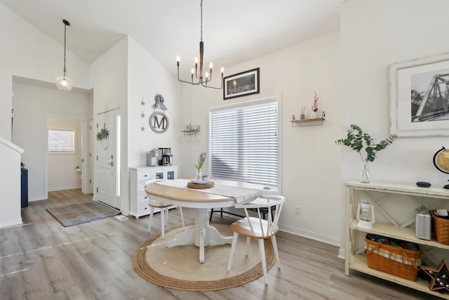 dining area with light wood finished floors, baseboards, a chandelier, and high vaulted ceiling