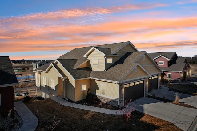 craftsman inspired home featuring a garage, concrete driveway, stone siding, roof with shingles, and a residential view