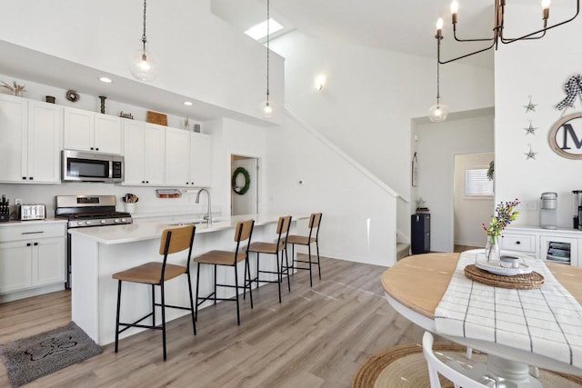 kitchen featuring stainless steel appliances, pendant lighting, light countertops, and white cabinets