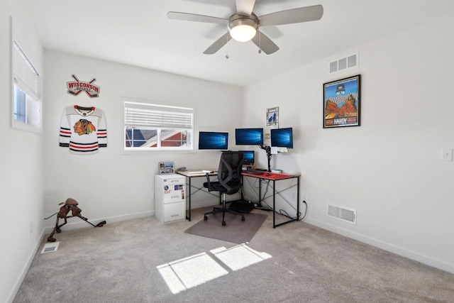 office area with baseboards, a ceiling fan, visible vents, and light colored carpet