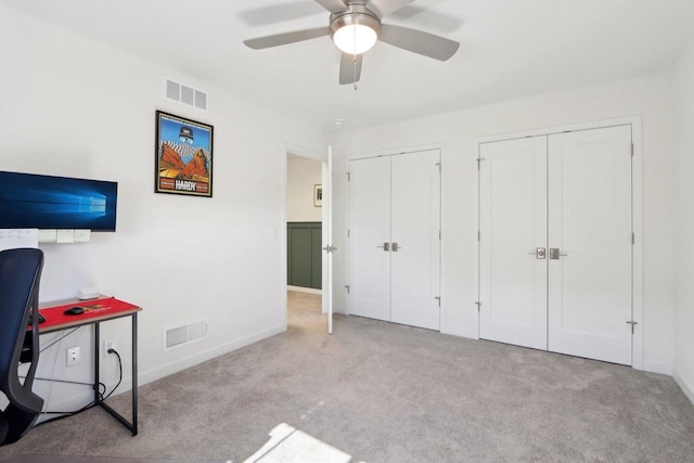 bedroom with baseboards, two closets, visible vents, and light colored carpet