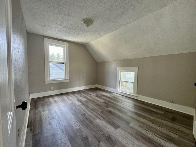 additional living space with lofted ceiling, baseboards, and dark wood finished floors