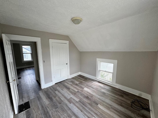 bonus room with a wealth of natural light, vaulted ceiling, baseboards, and wood finished floors