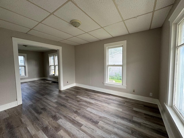 unfurnished room with dark wood-type flooring, a paneled ceiling, and baseboards