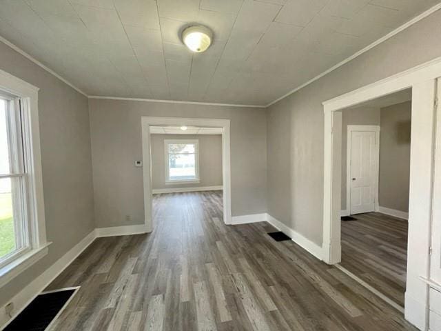 unfurnished dining area with ornamental molding, baseboards, and dark wood-style floors