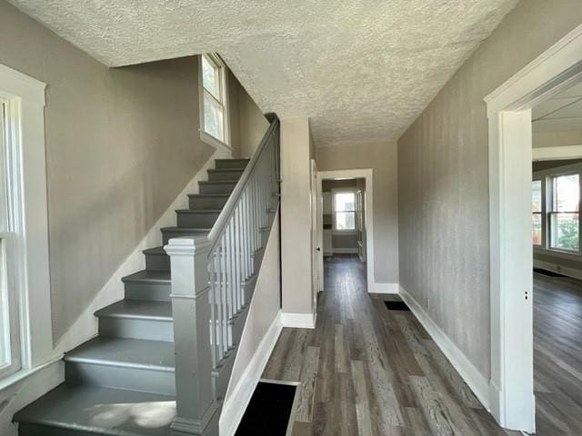 staircase featuring a textured ceiling, baseboards, and wood finished floors