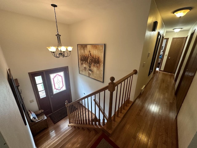 entryway with dark wood-type flooring and a chandelier