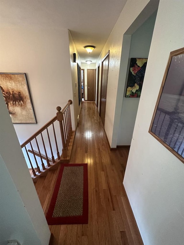 corridor with dark wood-type flooring and an upstairs landing