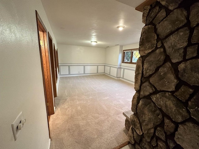 basement featuring light carpet and wainscoting