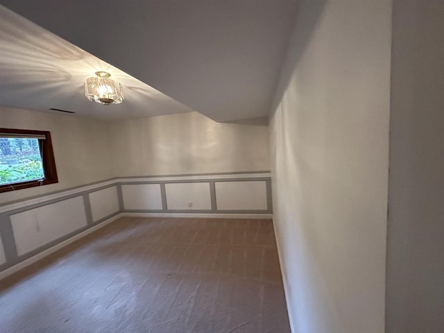 spare room with dark colored carpet, a wainscoted wall, a decorative wall, and visible vents