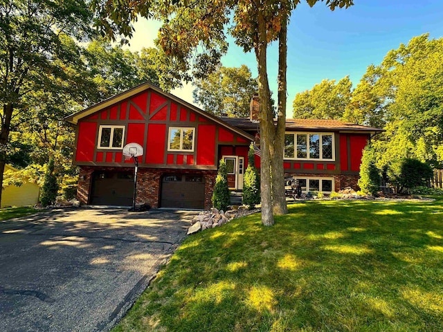 view of front facade featuring driveway, brick siding, a chimney, an attached garage, and a front yard