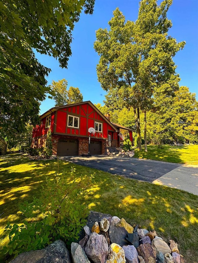 exterior space featuring aphalt driveway, a front yard, brick siding, and a garage