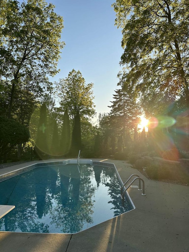 pool at dusk with a patio area and an outdoor pool