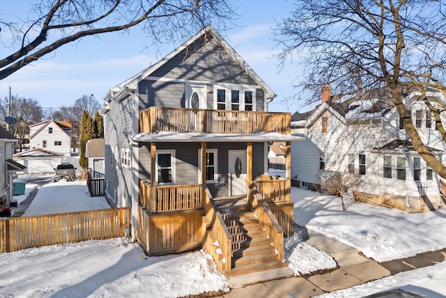 view of front facade featuring covered porch, fence, and a balcony