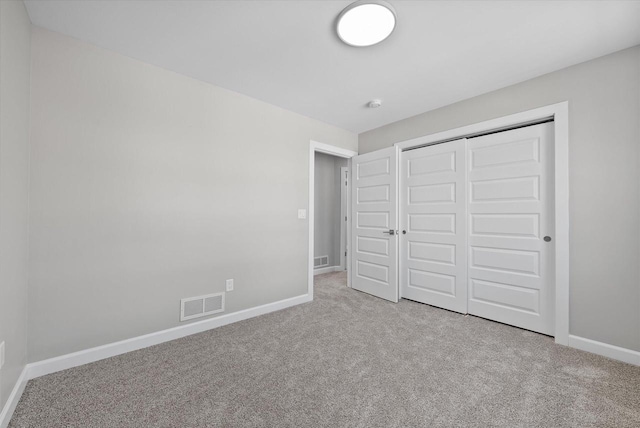 unfurnished bedroom featuring a closet, light carpet, visible vents, and baseboards