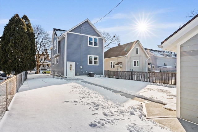 snow covered back of property with a residential view and fence