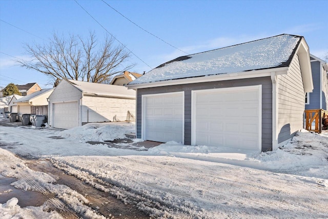 snow covered garage with a detached garage