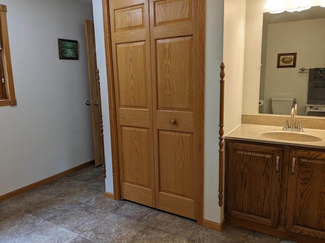 bathroom with a closet, baseboards, vanity, and toilet