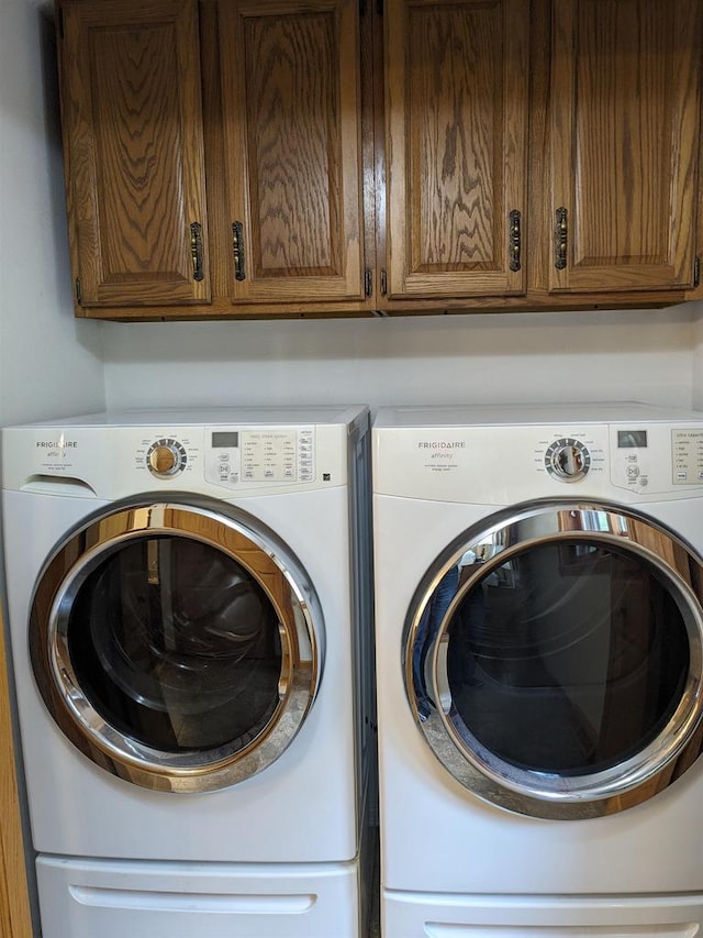 clothes washing area featuring washer and clothes dryer and cabinet space