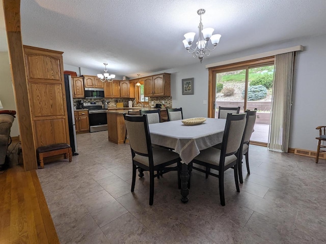 dining space featuring a textured ceiling, baseboards, visible vents, and an inviting chandelier