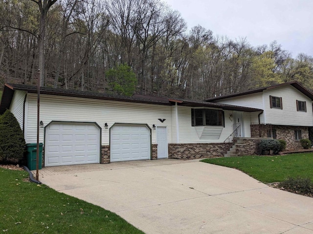 split level home with driveway, a front yard, a garage, and brick siding