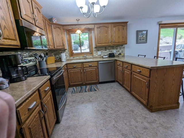 kitchen with a peninsula, stainless steel appliances, hanging light fixtures, light countertops, and brown cabinets