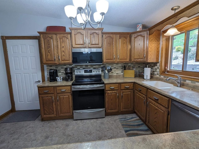 kitchen with a sink, light countertops, appliances with stainless steel finishes, brown cabinetry, and pendant lighting