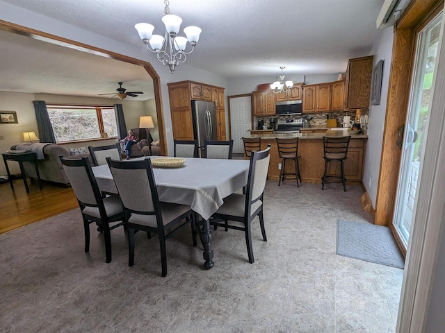 dining space featuring light floors and ceiling fan with notable chandelier