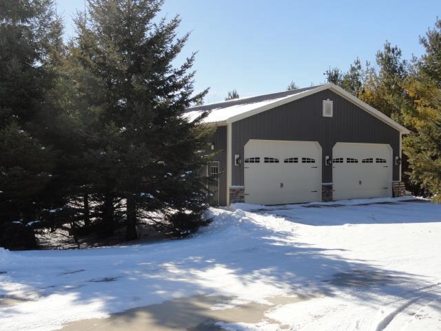N5194 Blue Valley Rd, Hartford, WI 53027 - view of snow covered exterior with a detached garage and stone siding