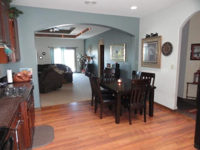 N5194 Blue Valley Rd, Hartford, WI 53027 - dining area with arched walkways, ceiling fan, light wood-style floors, a tray ceiling, and recessed lighting