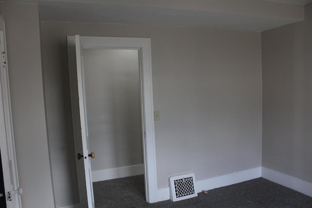 unfurnished room featuring baseboards, visible vents, and dark colored carpet