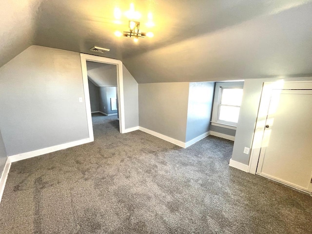 additional living space with dark colored carpet, visible vents, vaulted ceiling, and baseboards