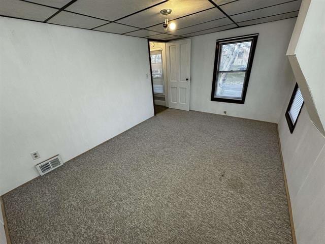 carpeted empty room with a paneled ceiling and visible vents