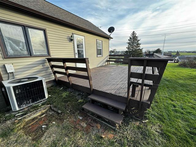 wooden terrace featuring cooling unit and a lawn