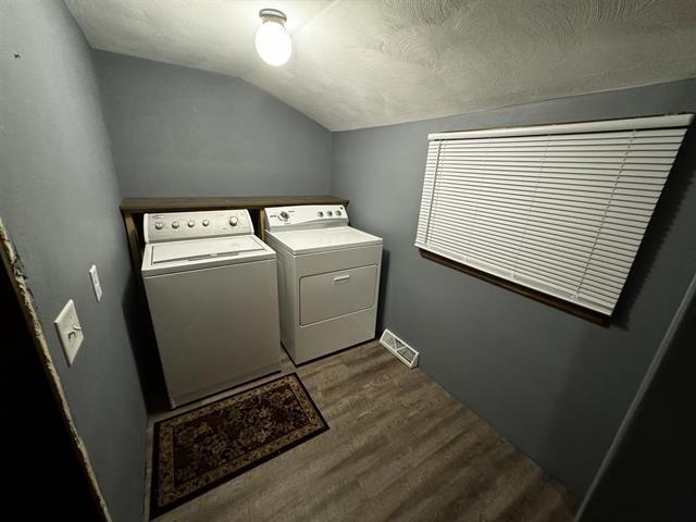 laundry area with visible vents, washing machine and dryer, a textured ceiling, wood finished floors, and laundry area