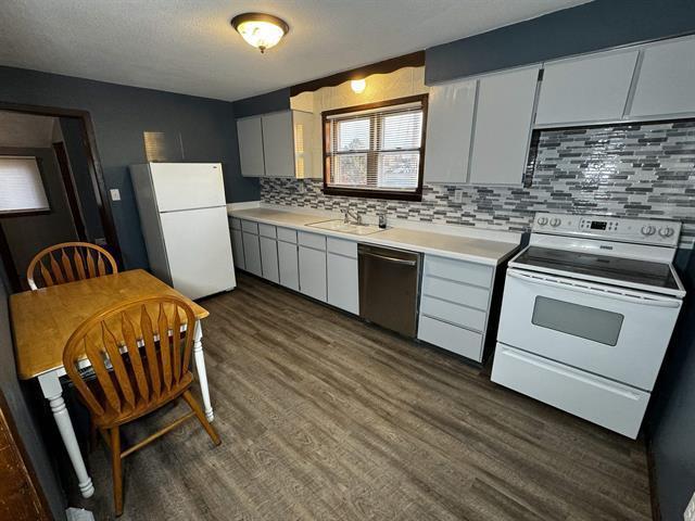 kitchen featuring dark wood-style floors, tasteful backsplash, light countertops, white cabinetry, and white appliances