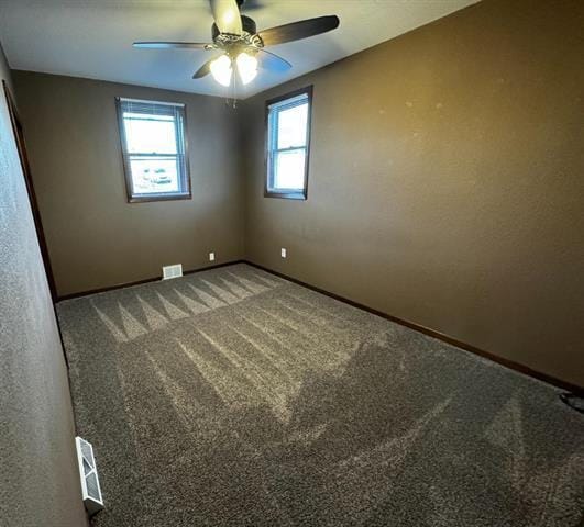 carpeted empty room featuring a ceiling fan, visible vents, and baseboards