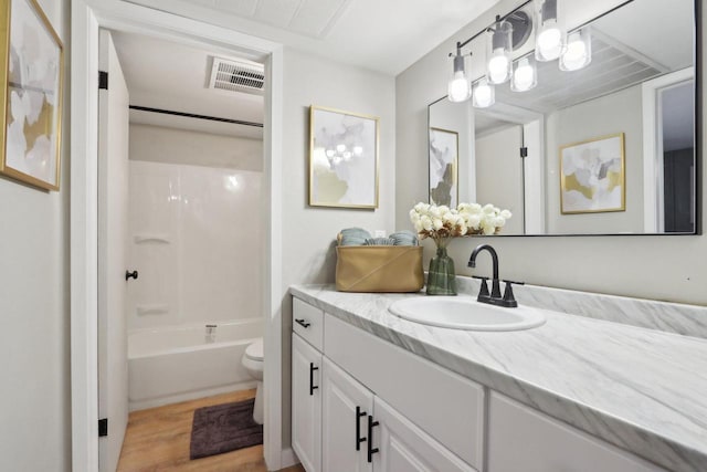 bathroom with visible vents, toilet, shower / tub combination, wood finished floors, and vanity