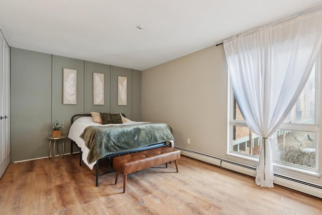 bedroom featuring light wood-type flooring, a baseboard radiator, and multiple windows