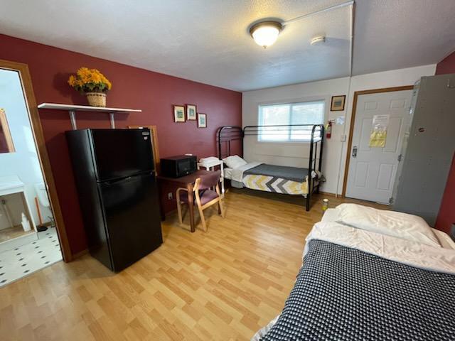 bedroom featuring freestanding refrigerator and wood finished floors