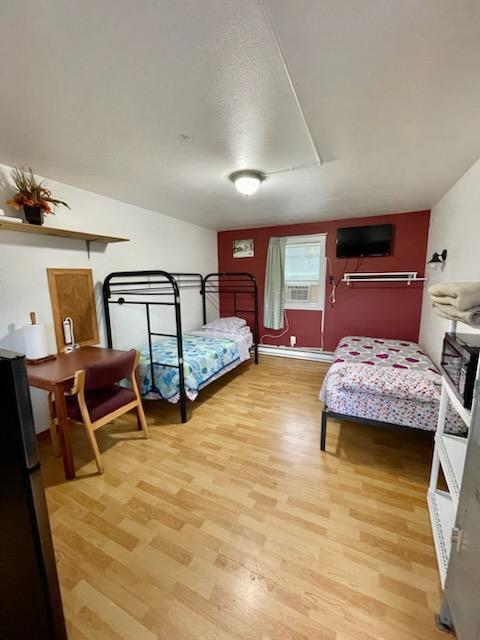 bedroom with attic access, wood finished floors, and freestanding refrigerator