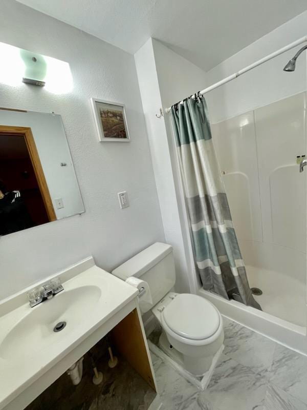 bathroom with a stall shower, marble finish floor, and a sink