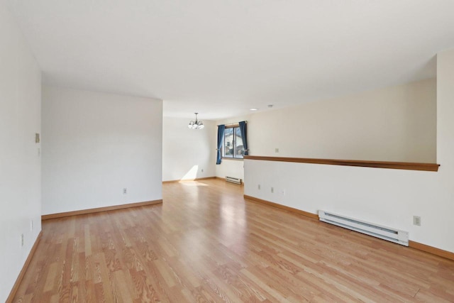 empty room with a chandelier, light wood-type flooring, baseboards, and a baseboard radiator