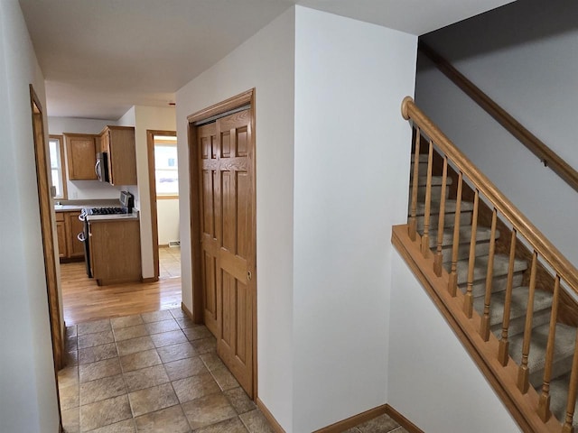 hall featuring stone finish flooring, stairway, and baseboards