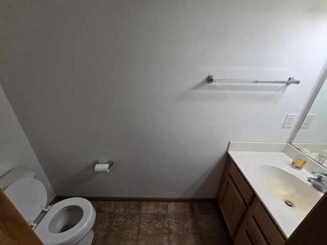 half bath with vanity, toilet, and baseboards